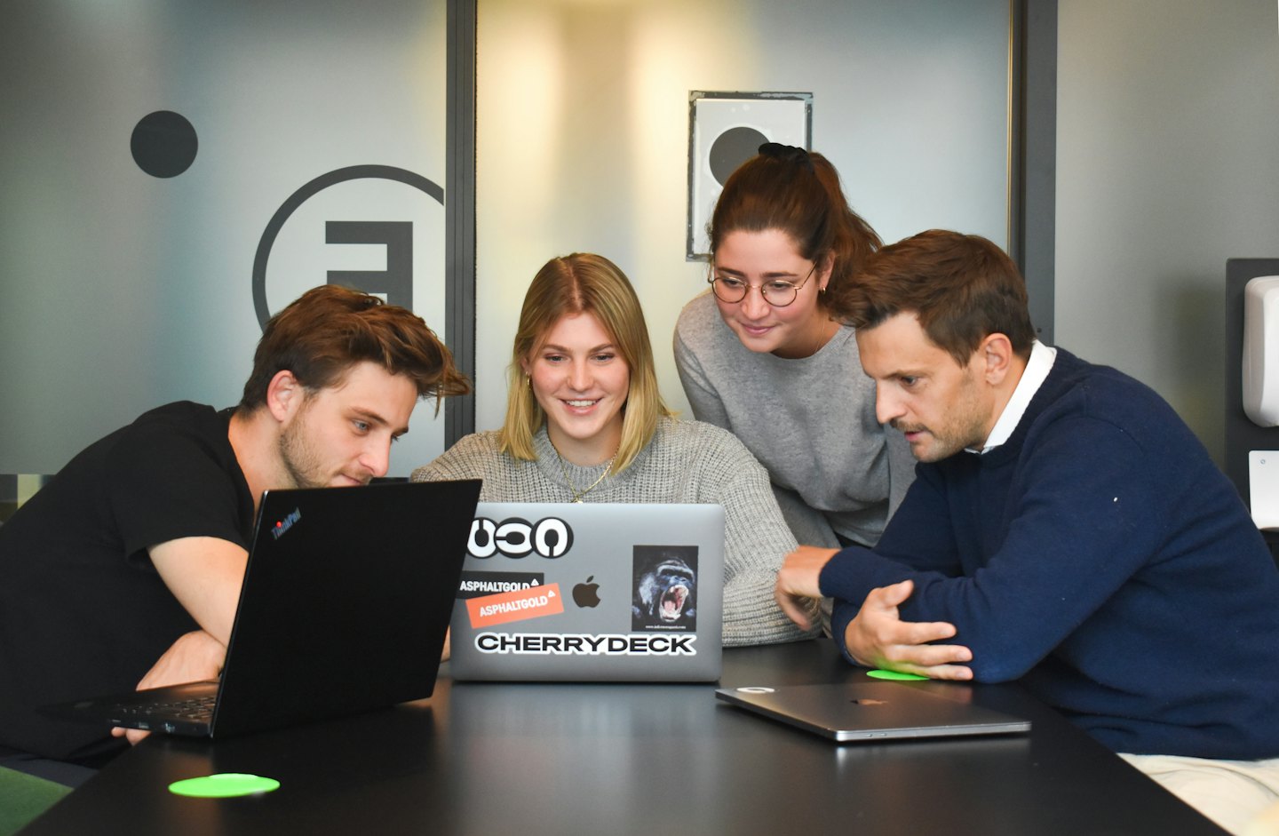 Quattro colleghi che collaborano al computer portatile a un tavolo.